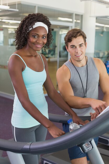 Fit vrouw op loopband in gesprek met personal trainer