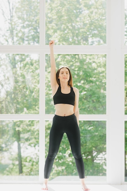 Fit vrouw pose yoga oefenen in studio over panoramisch raam