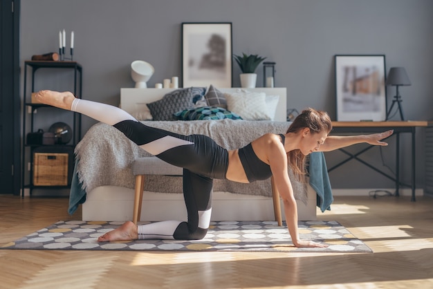 Fit vrouw uitoefenen thuis beoefenen van yoga.