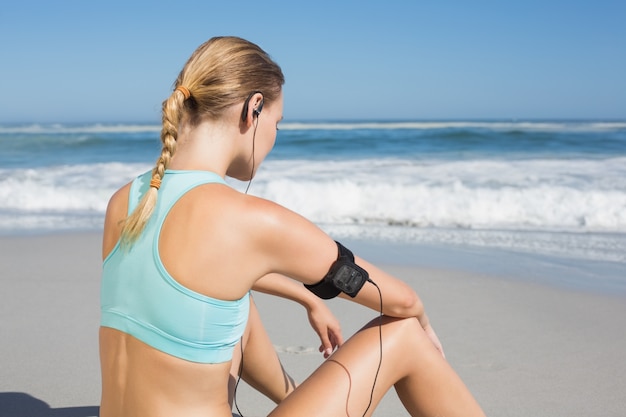 Fit vrouw zittend op het strand een pauze te nemen