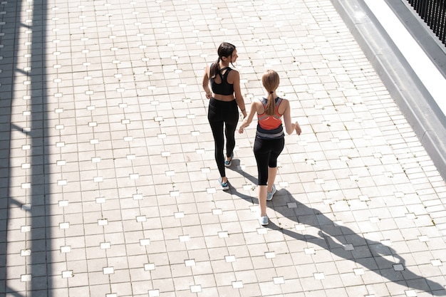 Fit vrouwen in sportkleding die buiten jogt en een gezonde levensstijl leidt.