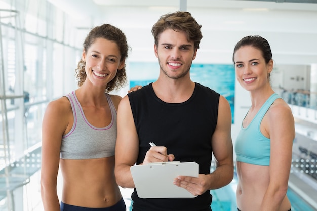 Fit vrouwen met trainer het maken van aantekeningen en lacht naar de camera