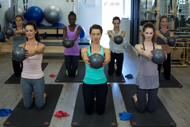 Fit vrouwen stretching oefening met fitness bal in sportschool