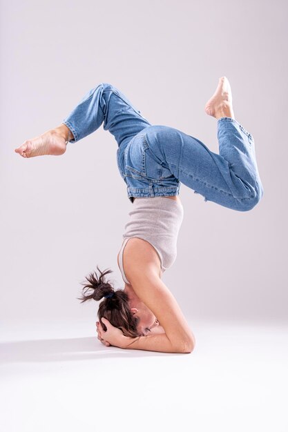 Fit woman acrobat in jeans stretching her legs. Acrobat woman stretching on the floor