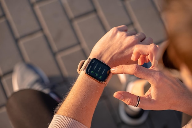 Fit woman checking smart watch wearable technology, sport smartwatch on fitness run walk outside. Top view from above with running shoes in street.