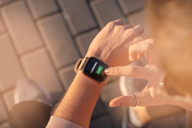 fit woman checking smart watch wearable technology, sport smartwatch on fitness run walk outside. top view from above with running shoes in street.