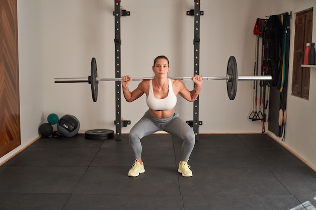 Fit woman doing barbell squats with heavy weights