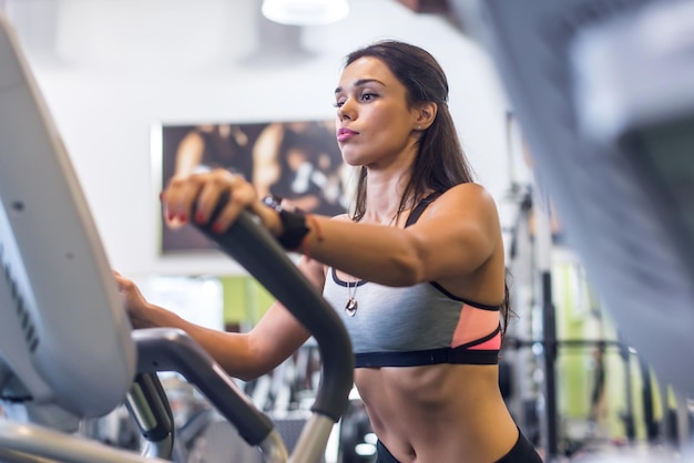 Fit woman doing cardio in an elliptical trainer in a gym