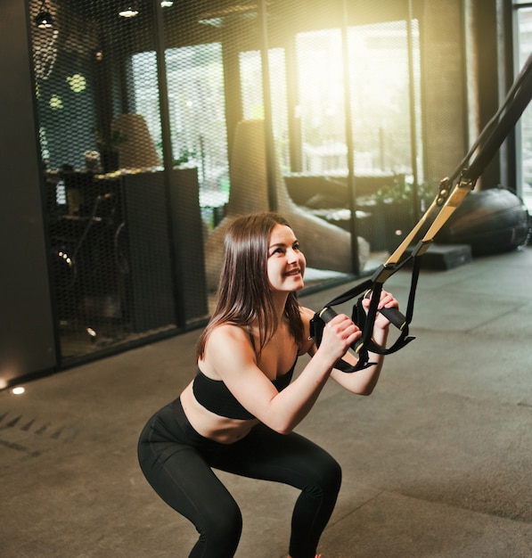 Montare la donna facendo esercizio con cinturino fitness in palestra. allenamento, allenamento funzionale. stile di vita sportivo