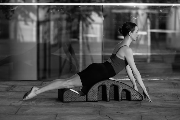 Fit woman doing pilates on arc barrel outdoors