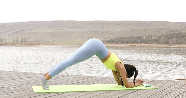 Donna adatta che fa esercizi di pilates di yoga della plancia della gamba sollevata.