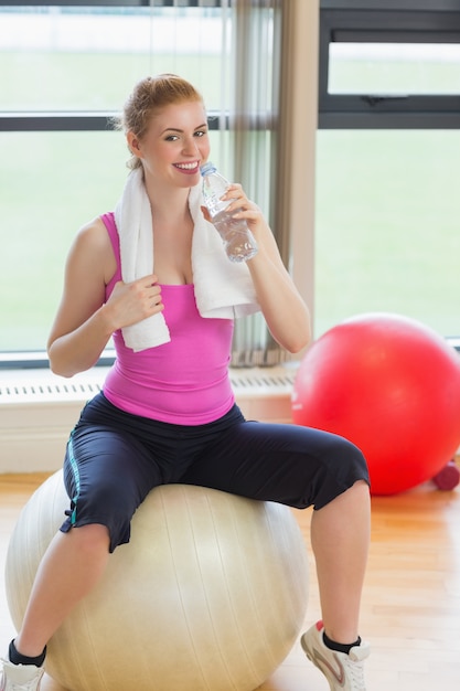 Fit woman on exercise ball with water bottle