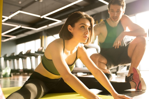 Fit woman exercising with coach in gym