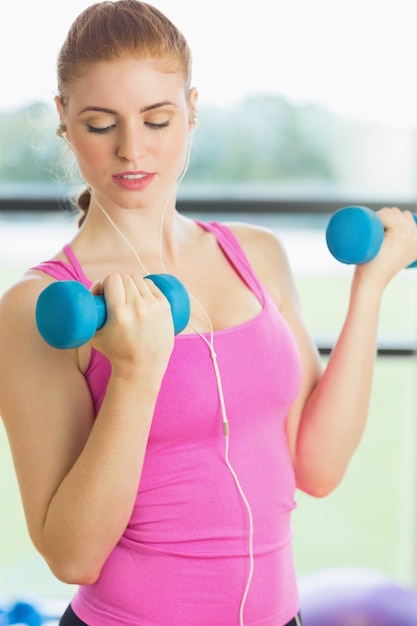 Fit woman exercising with dumbbells in fitness studio