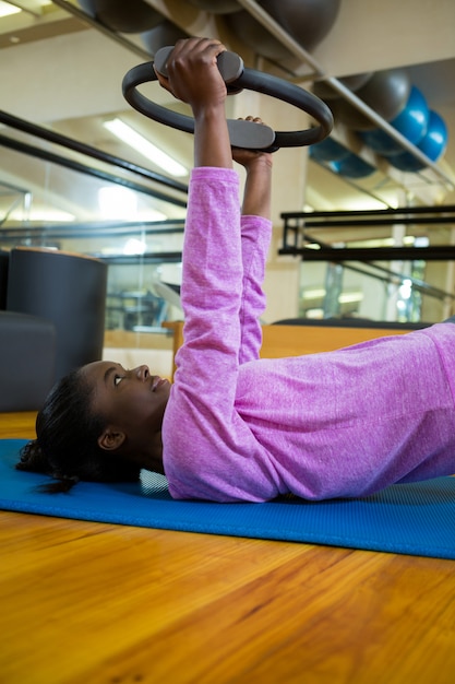 Fit woman exercising with pilates ring on mat