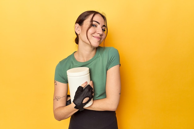 Fit woman holding a protein shake laughing and having fun