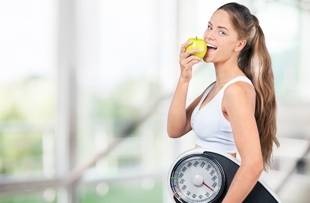 Fit woman holding a scale and apple