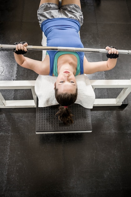 Photo fit woman lifting the barbell on bench at the gym