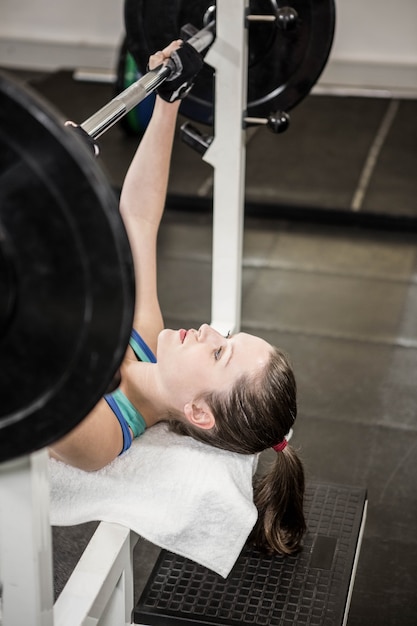 Fit woman lifting the barbell bench press in gym