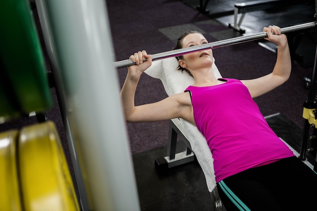 Foto la donna adatta che solleva il banco del bilanciere introduce la palestra