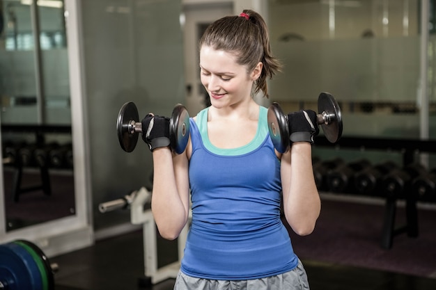 Fit woman lifting dumbbells at the gym