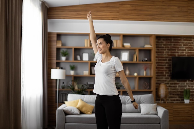 Fit woman lifting hands during workout at home