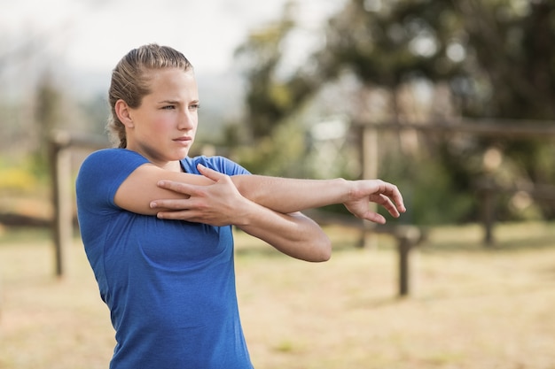 Montare la donna che esegue stretching esercizio durante il percorso ad ostacoli nel campo di addestramento