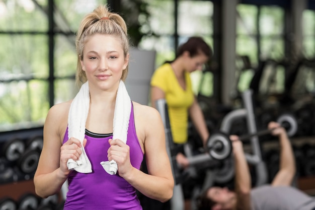 Fit woman posing while holding towel in gym