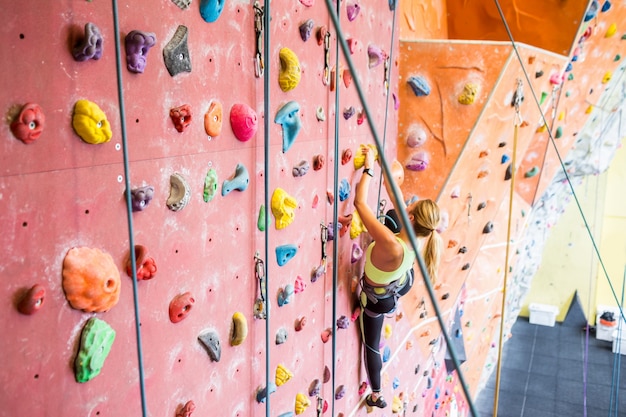 Fit woman rock climbing indoors