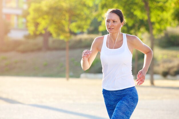 Fit woman running with earphones outside