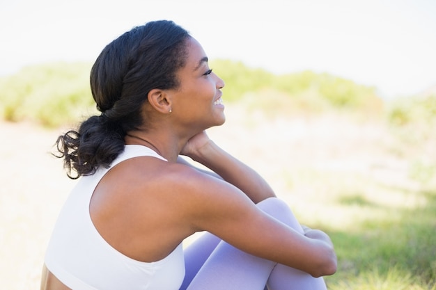 Fit woman sitting on grass smiling 