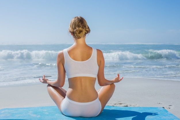 Fit woman sitting in lotus pose on the beach