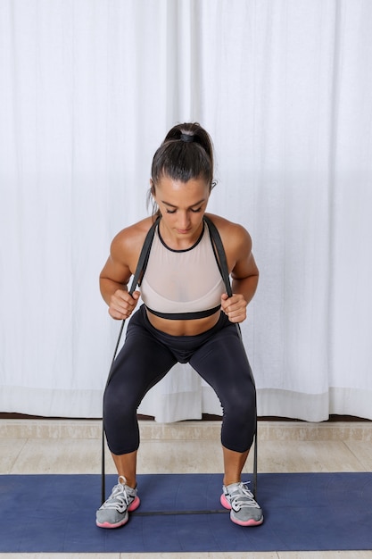 Photo fit woman squatting with resistance band