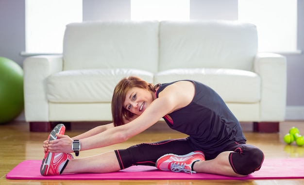 Fit woman stretching on exercise mat