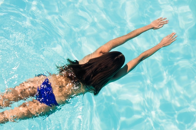 Fit woman swimming in the pool in a sunny day