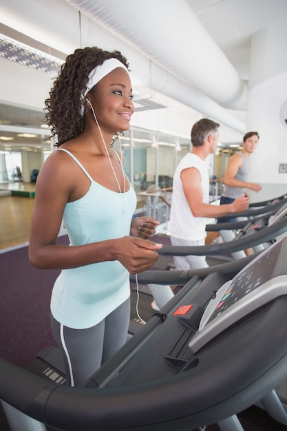 Photo fit woman on treadmill listening to music