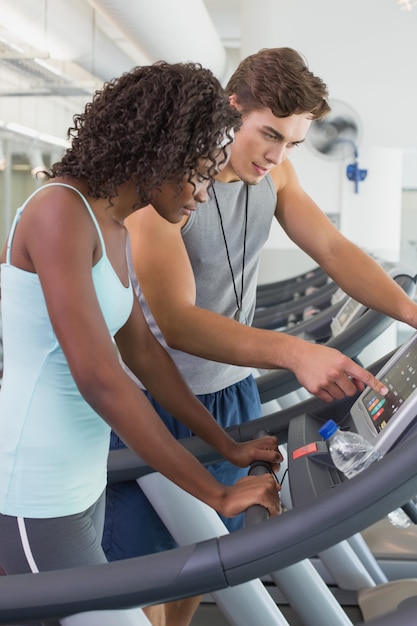 Photo fit woman on treadmill talking to personal trainer