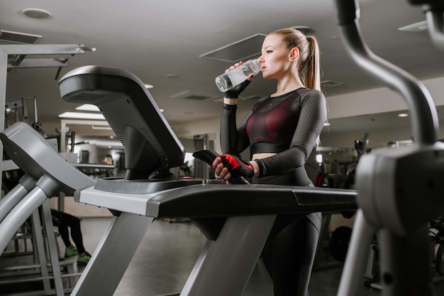 Fit woman on treadmill with bottlw of water in the gym