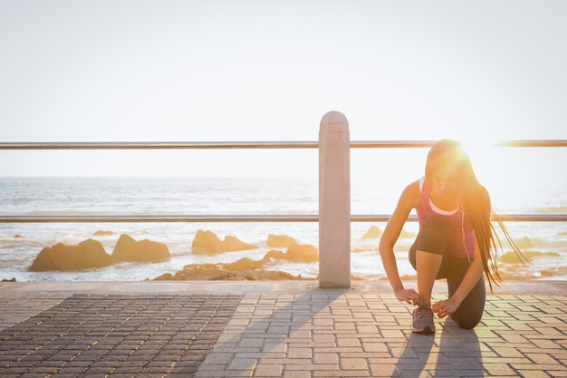 Fit woman tying her shoelace at promenade