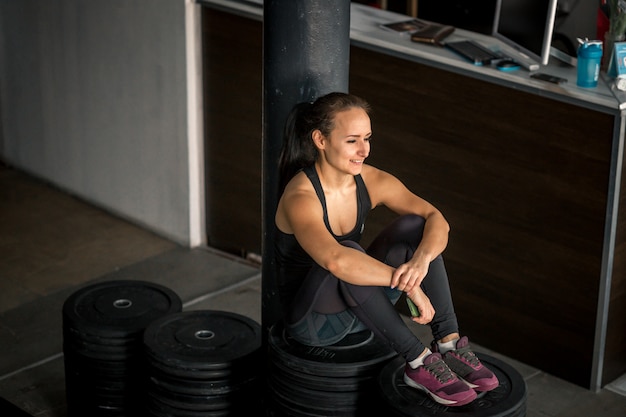 Photo fit woman using smartphone at gym