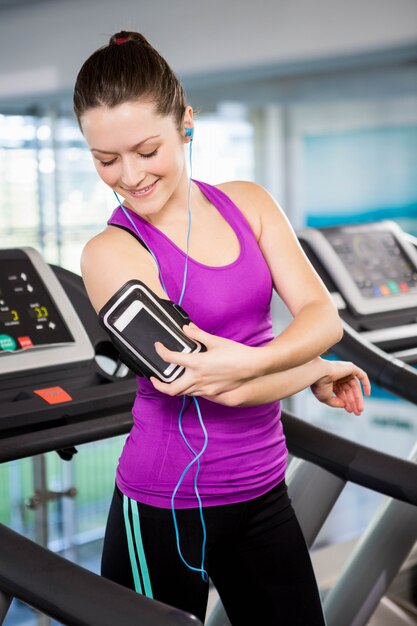 Fit woman using smartphone on treadmill at the gym