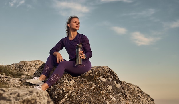 Fit woman with bottle of water resting in nature