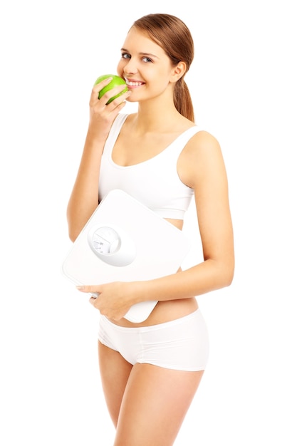 fit woman with a green apple and bathroom scales on white background