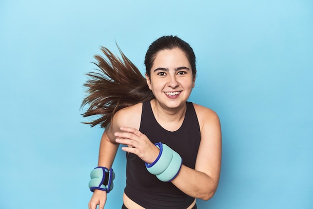 Fit woman with wrist weights against a blue backdrop