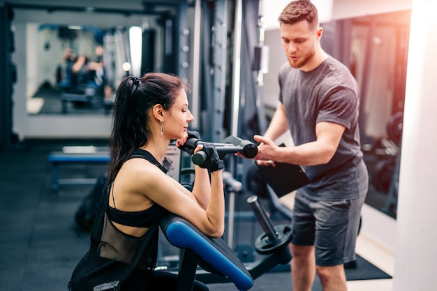 Fit woman working out with trainer at the gym