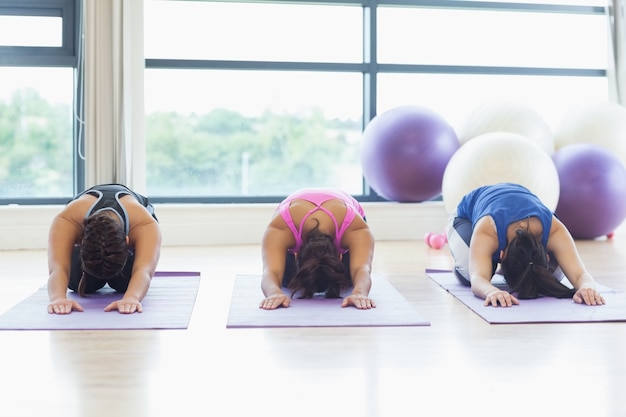 Fit women bending over on exercise mats in fitness studio