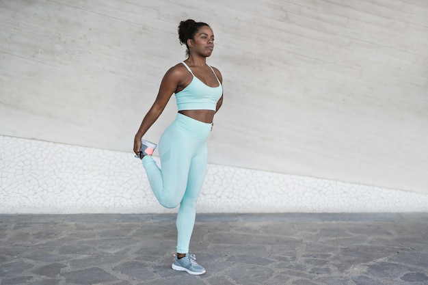 Fit young afircan woman doing stretching exercise after sport workout in the city