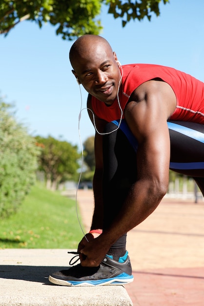 Fit young black guy tying shoe laces before a run