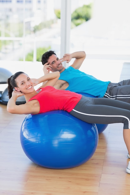 Photo fit young couple exercising on fitness balls at gym