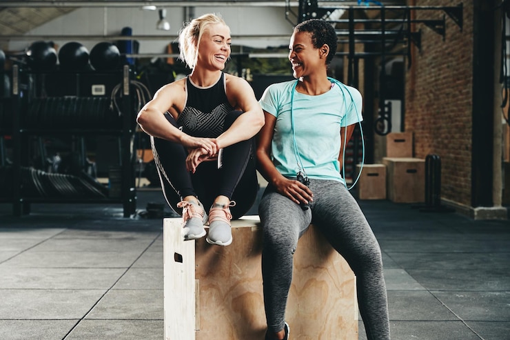 Photo fit young female friends laughing together after a gym workout